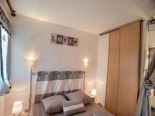 - une chambre dotée d'un lit avec un signe d'amour sur le mur dans l'établissement Appartement Lamalou 1er étage, animaux admis, proche centre et thermes - FR-1-451-100, à Lamalou-les-Bains