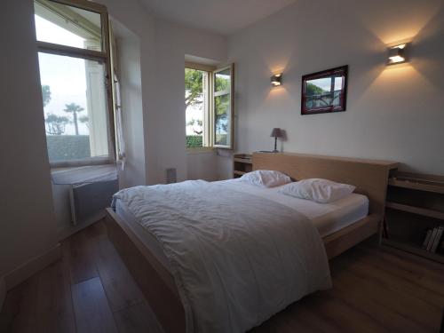 une chambre avec un lit et deux fenêtres dans l'établissement Appartement en Centre-Ville avec Terrasse et Parking, Accès Direct à la Plage - FR-1-474-4, à Arcachon