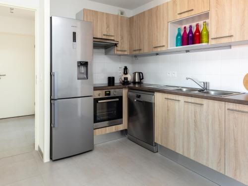 une cuisine avec des appareils en acier inoxydable et des armoires en bois dans l'établissement Superbe appartement neuf à deux pas de la plage avec balcon et parking privé à Capbreton - FR-1-239-387, à Capbreton