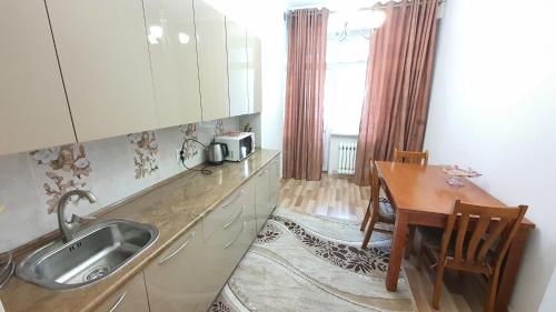 a kitchen with a sink and a table and a dining room at Stylish apartment in the city center in Bishkek