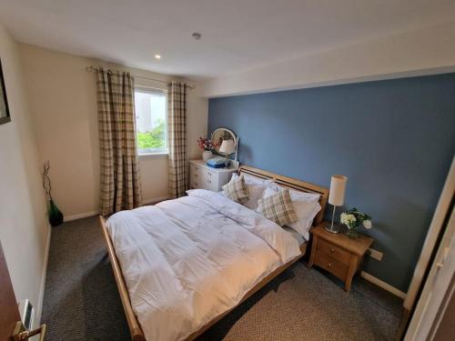 een slaapkamer met een bed en een blauwe muur bij Granite Getaways - Union Skyview in Aberdeen