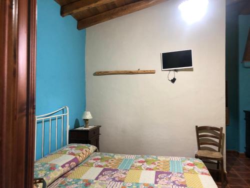 1 dormitorio con 1 cama y TV en la pared en Agriturismo Bingia Bonaria, en Pula