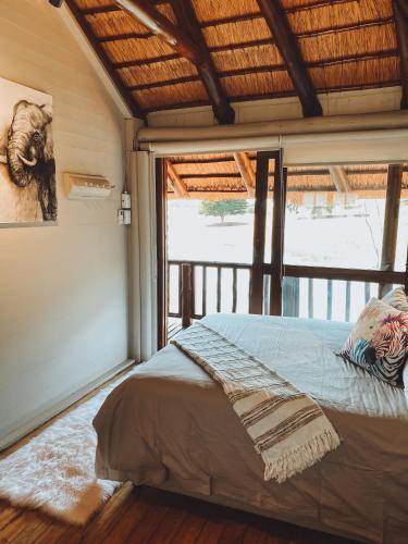 a bedroom with a bed and a large window at Hluhluwe Bush Camp in Hluhluwe