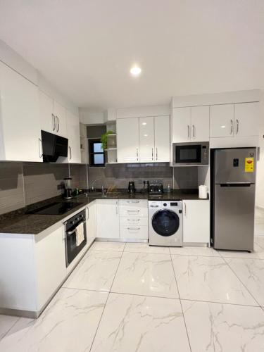 a white kitchen with white cabinets and a dishwasher at Luxury 1 bdrm Suite, Cantonments-Labone in Accra