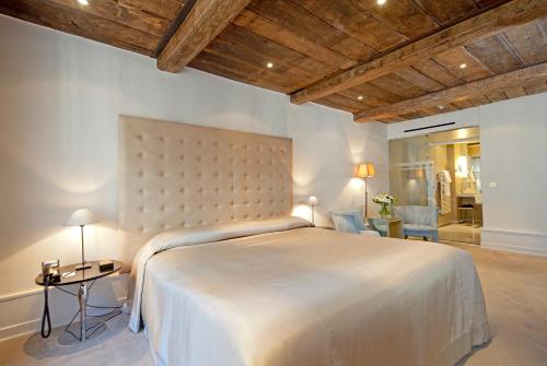 a bedroom with a large white bed with a wooden ceiling at Hotel Le Place d'Armes - Relais & Châteaux in Luxembourg