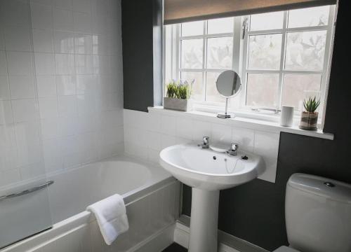 ein weißes Badezimmer mit einem Waschbecken, einer Badewanne und einem WC in der Unterkunft Walshford Lodge in Cowthorpe