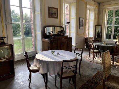 une salle à manger avec une table, des chaises et des fenêtres dans l'établissement Le Domaine de Toussacq, à Villenauxe-la-Petite