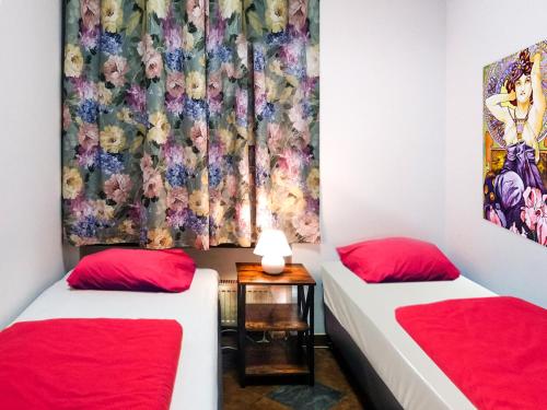 2 Einzelbetten in einem Zimmer mit roten Kissen in der Unterkunft Music Hostel Piotrkowska in Łódź