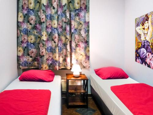 ウッチにあるMusic Hostel Piotrkowskaの赤い枕が備わる客室内のツインベッド2台