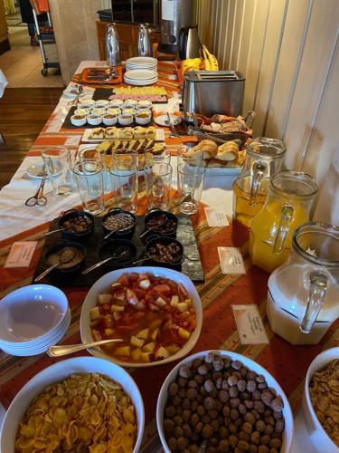 Una mesa con muchos tipos diferentes de comida sobre ella. en Hostería Suiza - Ex Casita Suiza, en San Carlos de Bariloche