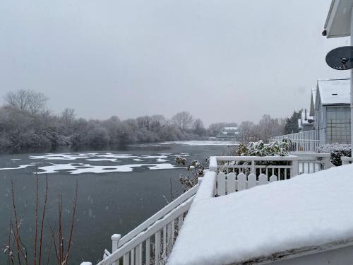 a view of a river with snow on a balcony at Herons Hideout in South Cerney