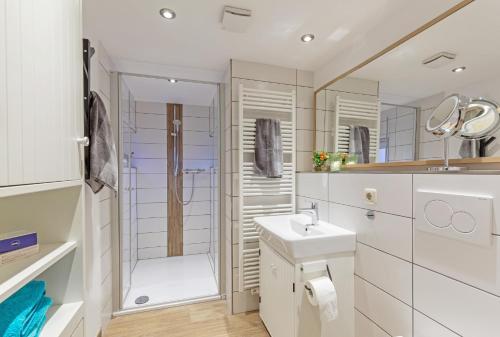La salle de bains blanche est pourvue d'une douche et d'un lavabo. dans l'établissement Ferienhof Marquardt Fewo Mohnblume, à Wenkendorf
