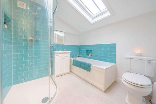 uma casa de banho com um WC e um chuveiro com azulejos azuis em The Cider Barn, Luxury for 2 with beautiful views. em Ledbury