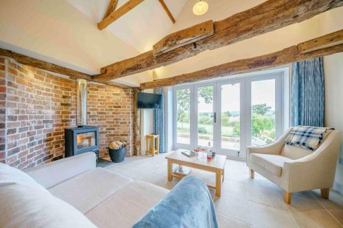 a living room with a fireplace and a brick wall at The Cider Barn, Luxury for 2 with beautiful views. in Ledbury