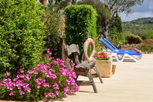 a garden with two chairs and flowers and bushes at Finca Teuler Petit in Caʼs Concos