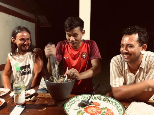 a group of three men sitting at a table eating food at Vera Sunset homestay local experience with lao family in Muang Không