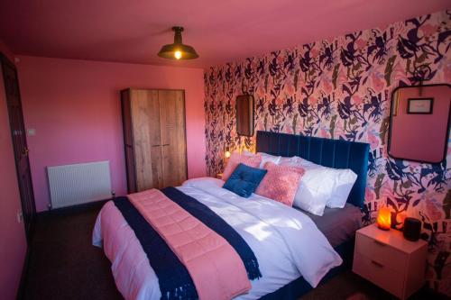 a bedroom with a bed with pink and purple walls at The Stables - Quirky one bed holiday home with wood fired hot tub in Rudston
