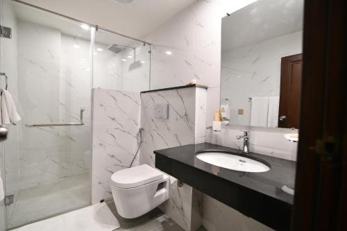 a bathroom with a sink and a toilet and a shower at Royal Regency Hotel in Islamabad