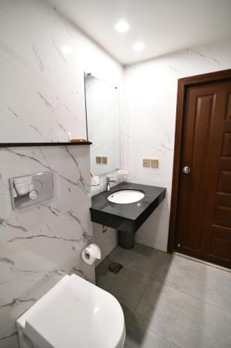 a bathroom with a white toilet and a sink at Royal Regency Hotel in Islamabad
