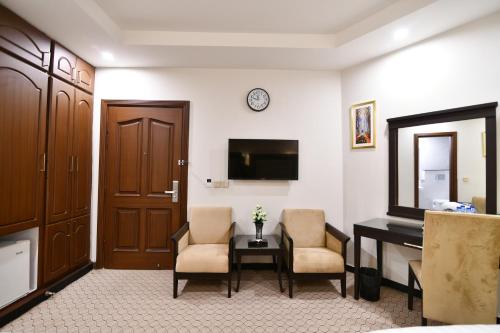 a room with a desk and two chairs and a television at Royal Regency Hotel in Islamabad