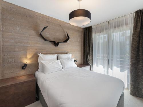 - une chambre avec un lit blanc et une horloge murale dans l'établissement Appartement à Rochebrune avec Piscine, Sauna et Proximité Centre Megève - FR-1-569-29, à Megève