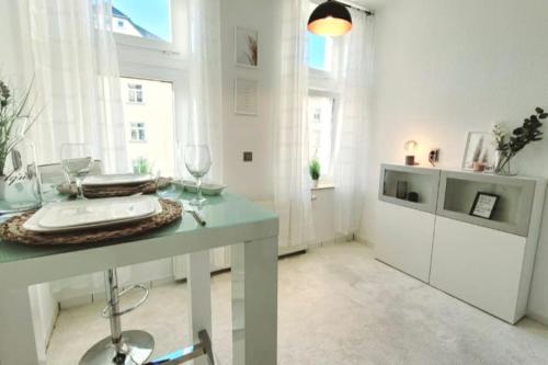 Habitación blanca con mesa y copas de vino en Gemütliches helles Appartement en Dresden