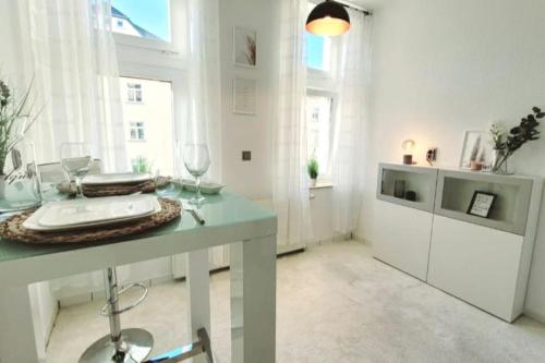 a white room with a table with wine glasses at Gemütliches helles Appartement in Dresden