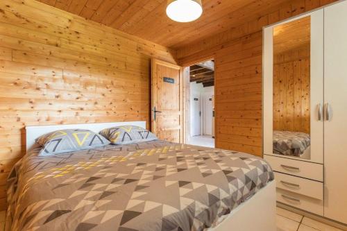 1 dormitorio con 1 cama en una pared de madera en Le cocon d'Aurore, 
