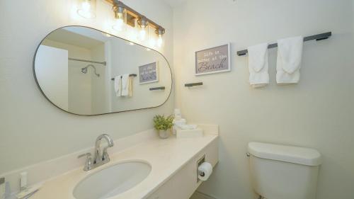 a white bathroom with a sink and a mirror at Heated Pool, Bunk Beds, King Bed, Huge TV, Marina, Tiki Bar in Sarasota