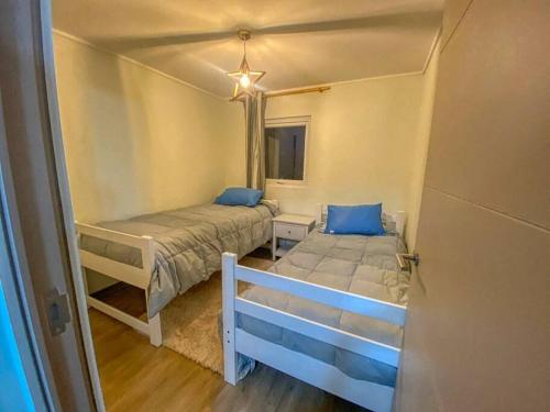 een kleine slaapkamer met 2 bedden en een raam bij Hermoso y acogedor departamento a un paso de todo! in Papudo