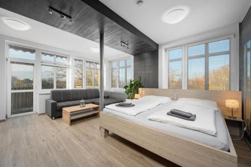 a bedroom with a bed and a couch and windows at Apartmá SunGarden Liberec in Liberec
