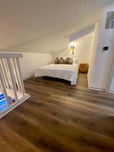 - une chambre avec un lit blanc et du parquet dans l'établissement DUPLEX 6P A BELLE-PLAGNE (2050 m), SKIS AUX PIEDS, EN PLEIN CŒURS DE LA STATION RESIDENCE LE BERYL., à Belle Plagne