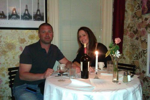 un hombre y una mujer sentados en una mesa con una botella de vino en Garden House Bed and Breakfast en Hannibal