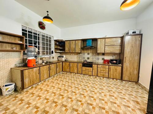 a kitchen with wooden cabinets and a tiled floor at Islamabad Travelodge Guest House in Rawalpindi