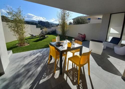 une table et des chaises sur une terrasse avec un jardin dans l'établissement Domaine de Pacciolello - Porticcio, à Porticcio