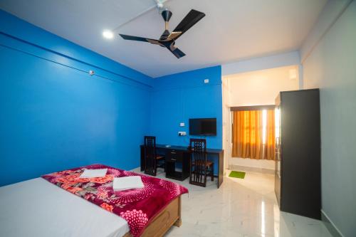 a blue bedroom with a bed and a table at Jungle Eco Mansion in Kāziranga