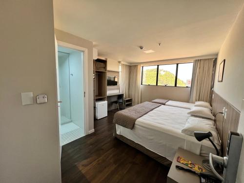 um quarto com uma cama, uma secretária e uma janela em Hotel 7 Itajaí em Itajaí