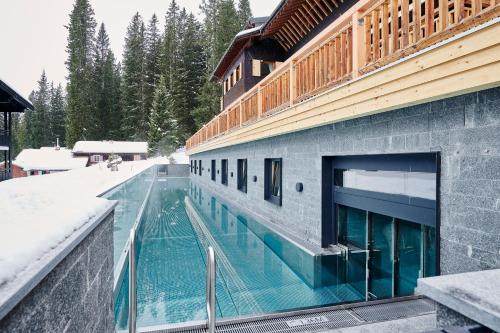 a swimming pool outside of a building in the snow at Hotel Petersboden in Lech am Arlberg