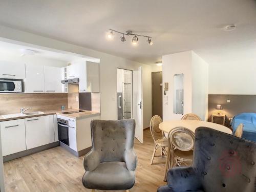 une cuisine et un salon avec une table et des chaises dans l'établissement Studio cosy à 50m des Thermes de Lamalou-les-Bains avec terrasse, wifi et animaux acceptés - FR-1-451-46, à Lamalou-les-Bains