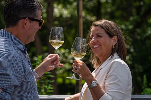 a man and a woman holding glasses of white wine at Boutique Hotel Slenaker Vallei - Buitengewoongenieten in Slenaken