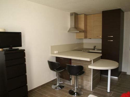 a small kitchen with a counter and stools and a tv at Studio chaleureux aux Adrets - Face aux pistes, 4ème étage, 2 pers, cuisine équipée - FR-1-557-28 in Les Adrets