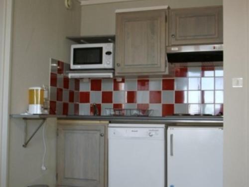 Il comprend une cuisine dotée d'un mur en carrelage rouge et blanc. dans l'établissement Chaleureux 2P, balcon, proche pistes & commerces - FR-1-557-99, à Les Adrets