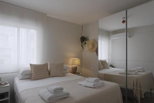 - une chambre blanche avec 2 lits et un miroir dans l'établissement Miradores Malagueta Beach, à Malaga