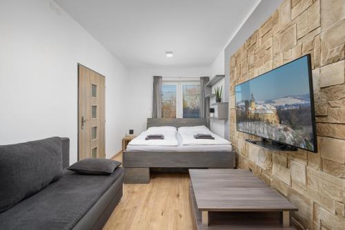 a living room with two beds and a tv on a wall at Apartmá SunGarden Liberec in Liberec