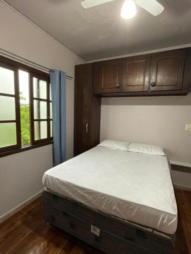 a small bedroom with a bed and a window at Pousada Belas Praia - Ribanceira in Imbituba