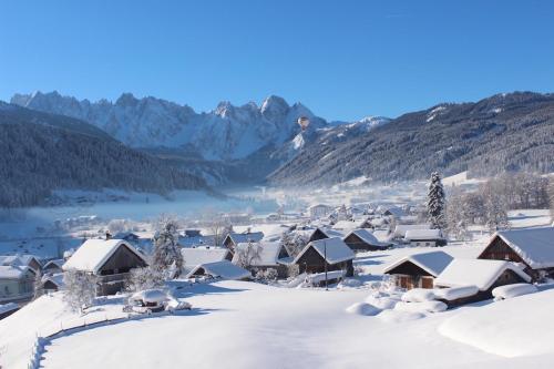 ein schneebedecktes Dorf mit Bergen im Hintergrund in der Unterkunft Dachstein 7 in Gosau