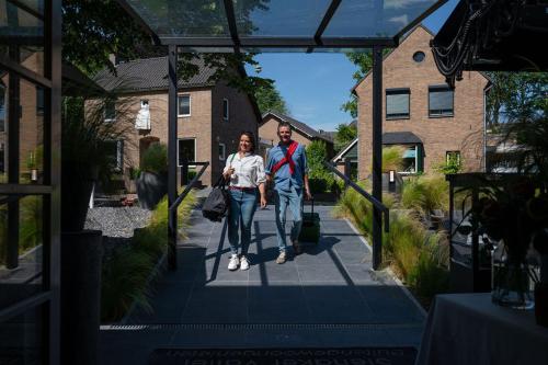 a man and a woman walking down a sidewalk at Boutique Hotel Slenaker Vallei - Buitengewoongenieten in Slenaken