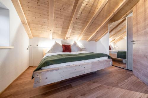 Cama grande en habitación con techo de madera en Alpenrose Ferienwohnungen en Lenggries