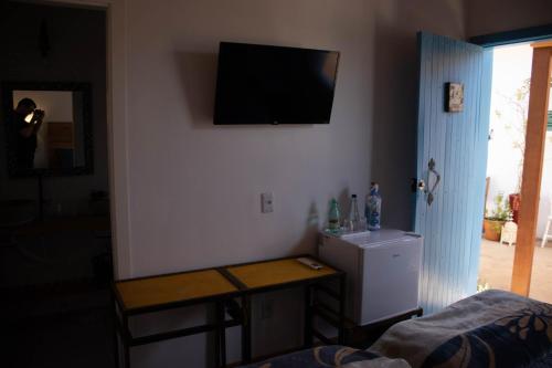 a room with a tv on the wall and a table at POUSADA TONS DA MANTIQUEIRA in Piranguçu