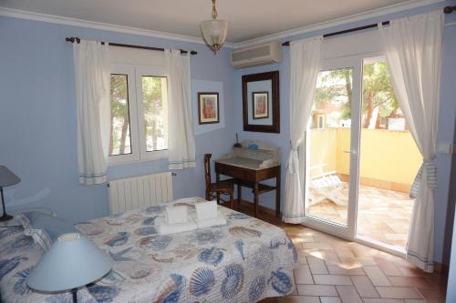 a bedroom with a bed and a desk and windows at RINCONCILLO in Denia